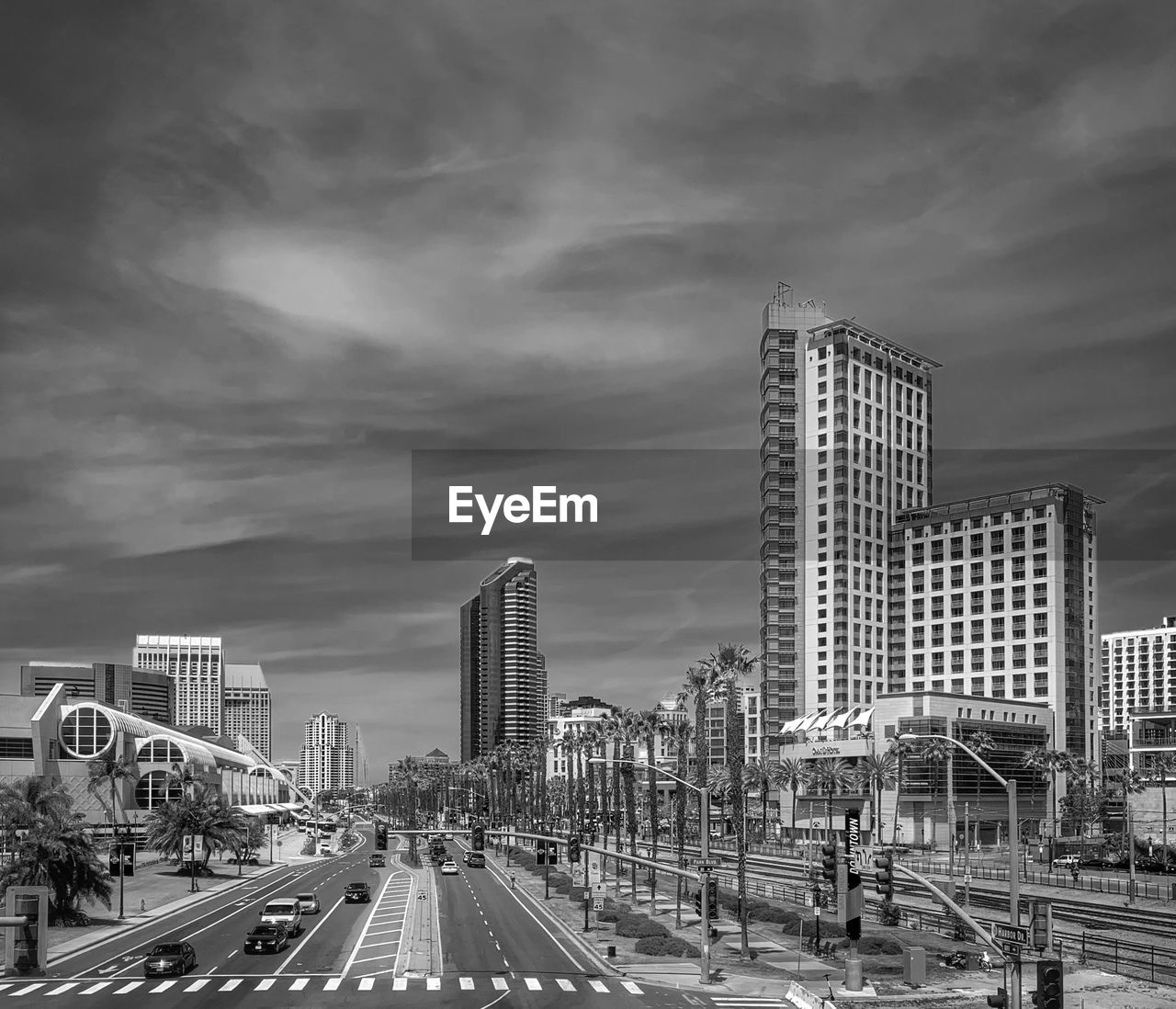 VEHICLES ON ROAD BY BUILDINGS AGAINST SKY