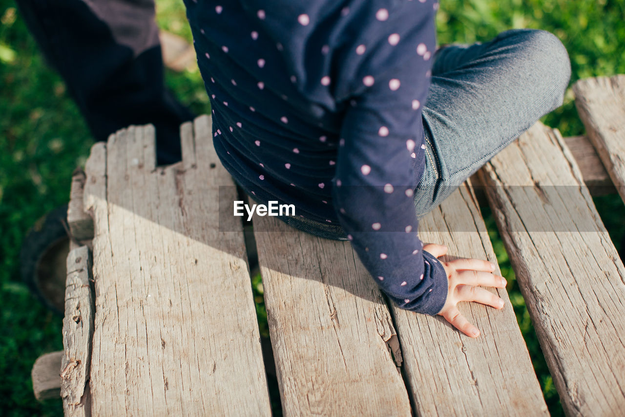 Low section of woman sitting on wood