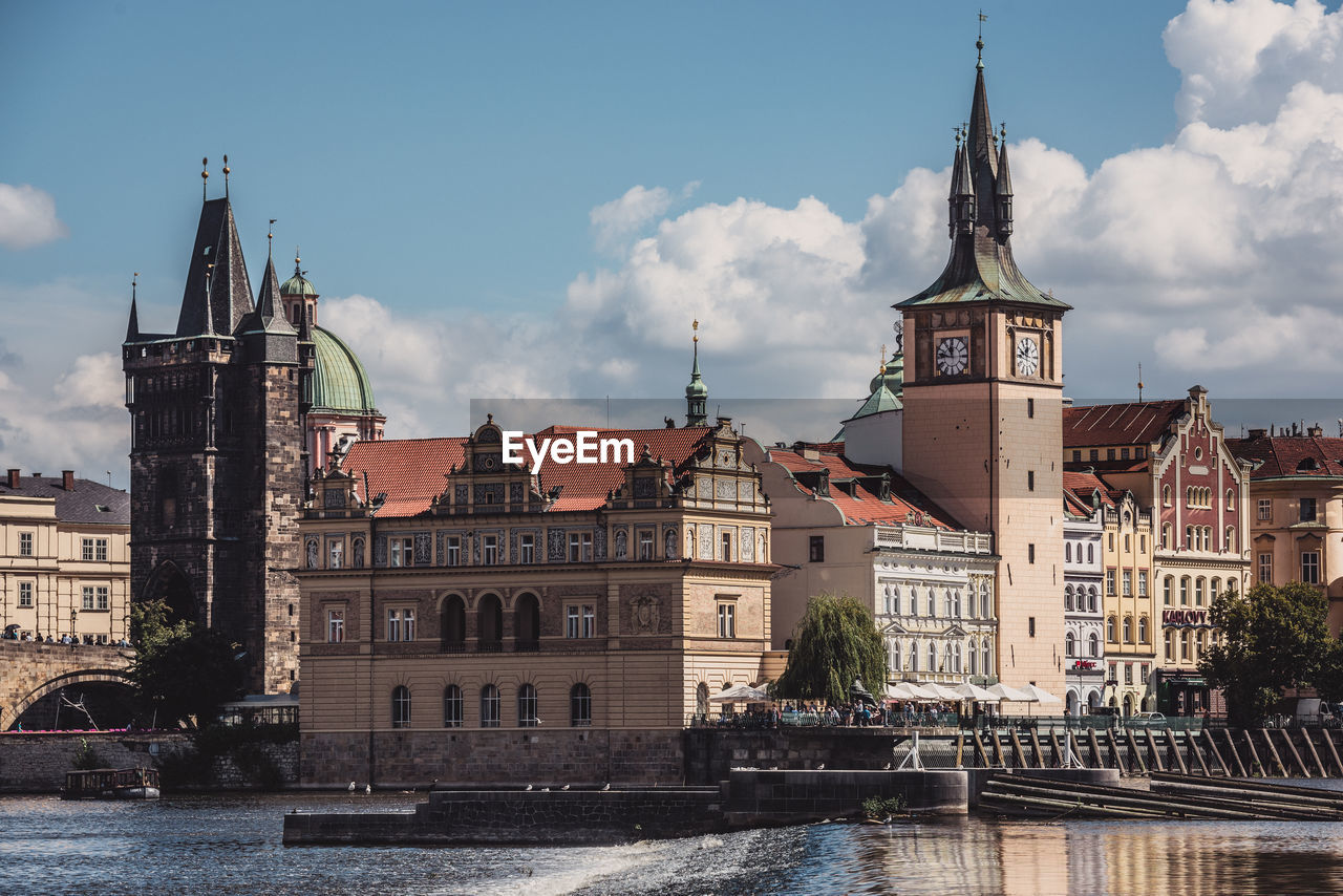 Buildings by river against sky in city