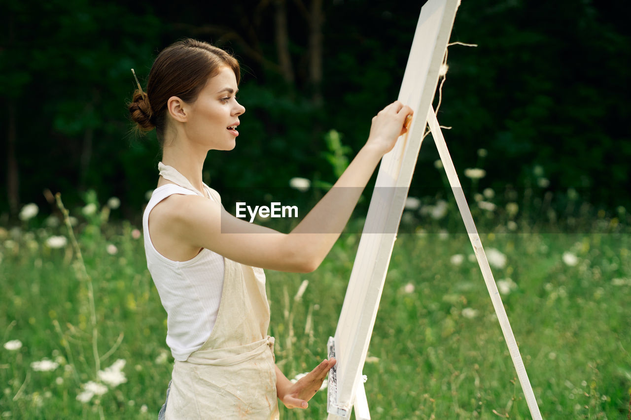 WOMAN STANDING ON FIELD AGAINST PLANTS