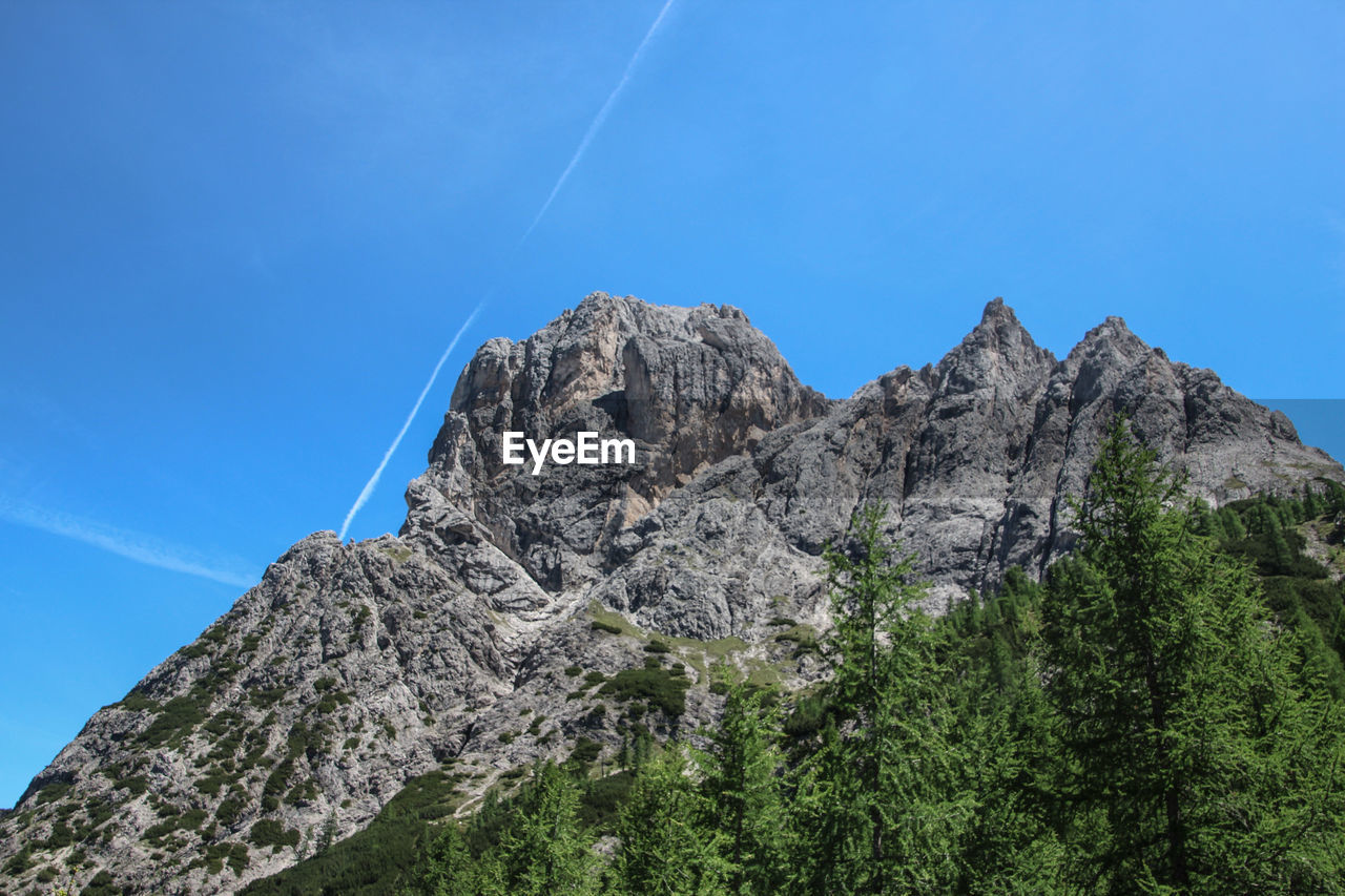 Low angle view of rocky mountains against clear blue sky