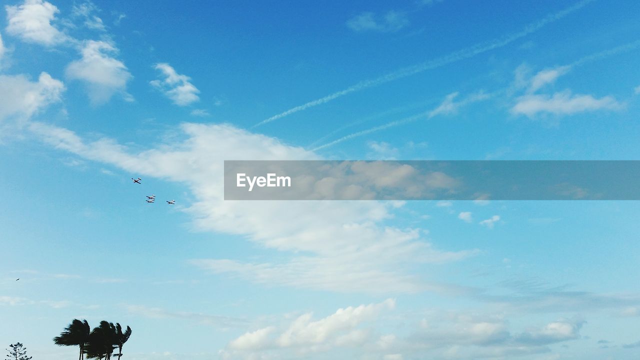 LOW ANGLE VIEW OF AIRPLANE FLYING AGAINST BLUE SKY