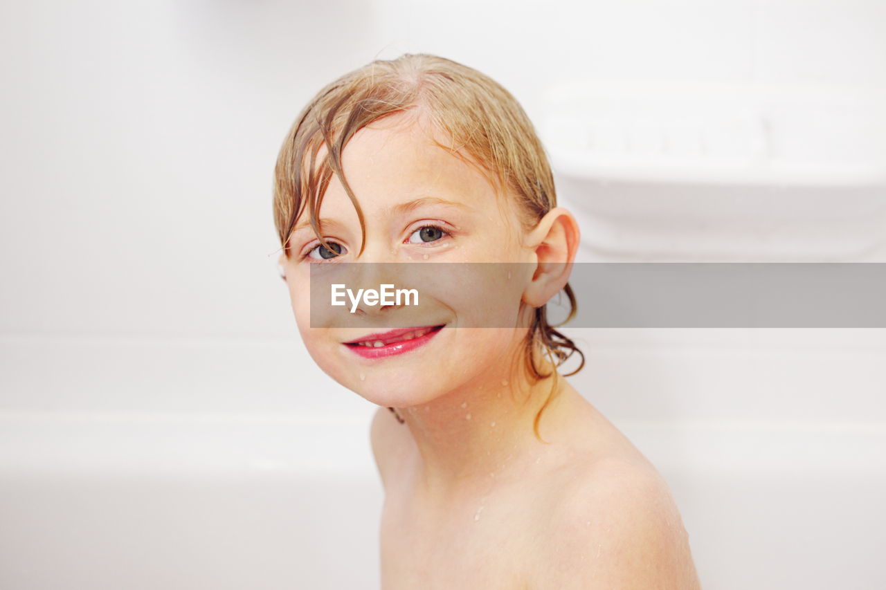 Portrait of smiling wet boy in bathtub