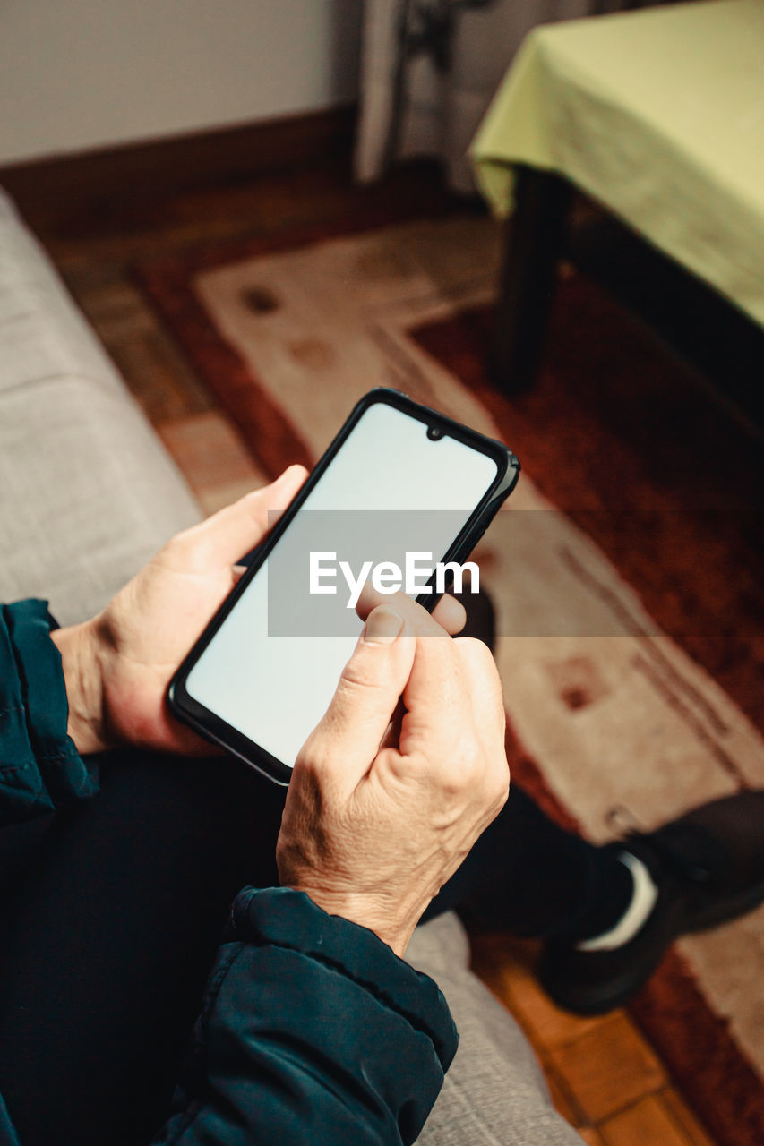 Cropped hand of man using mobile phone outdoors