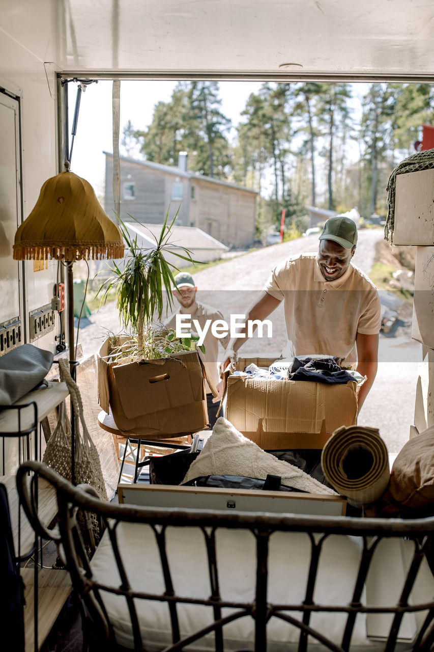 Multiracial delivery men picking cardboard boxes from truck