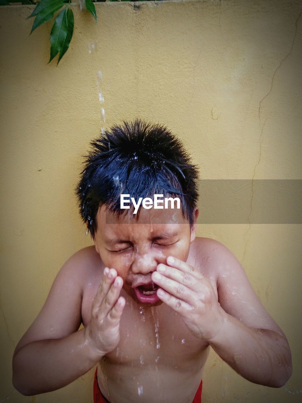 Shirtless boy taking bath outdoors