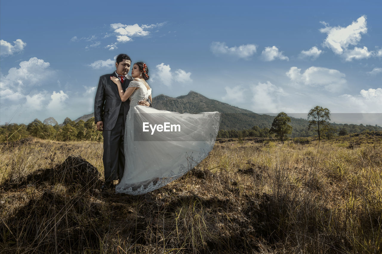 Rear view of couple on field against sky