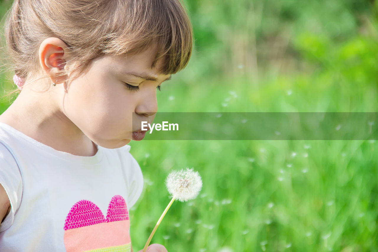 close-up of girl looking away while sitting on field