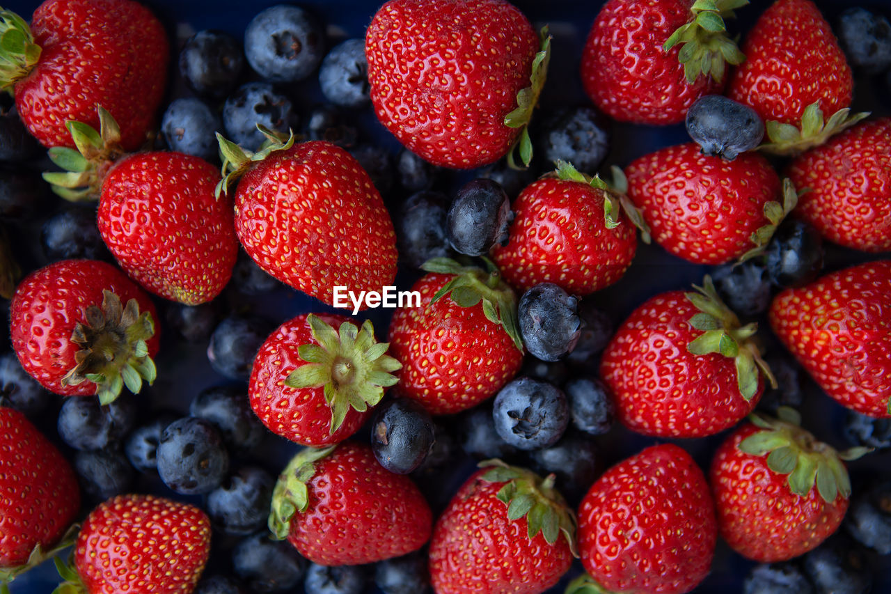 Background of assorted fresh berries of red juicy strawberries and blue blueberries close-up.