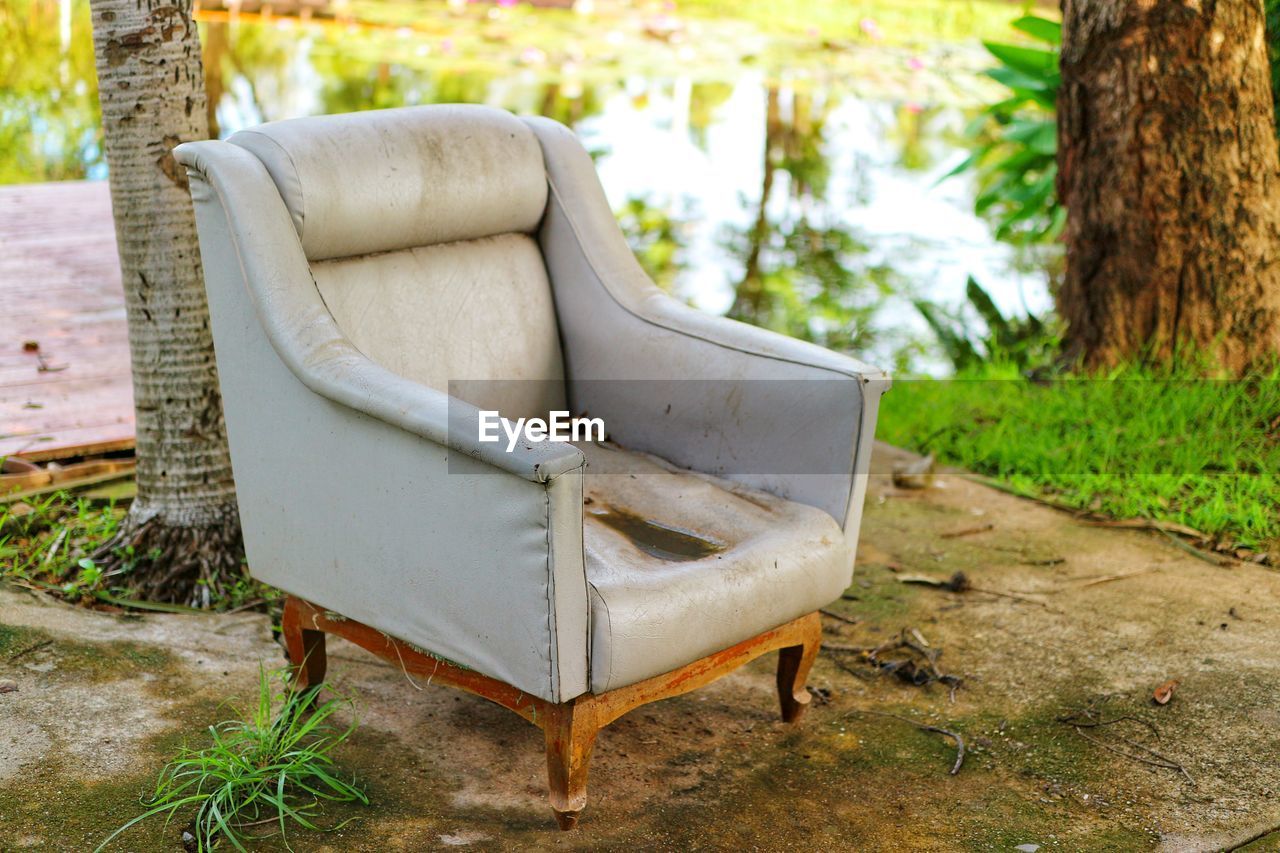 EMPTY BENCH ON FIELD BY TREE TRUNK