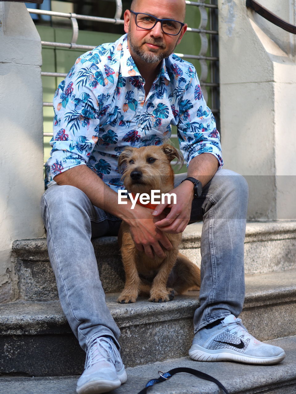 Portrait of man with dog sitting on staircase