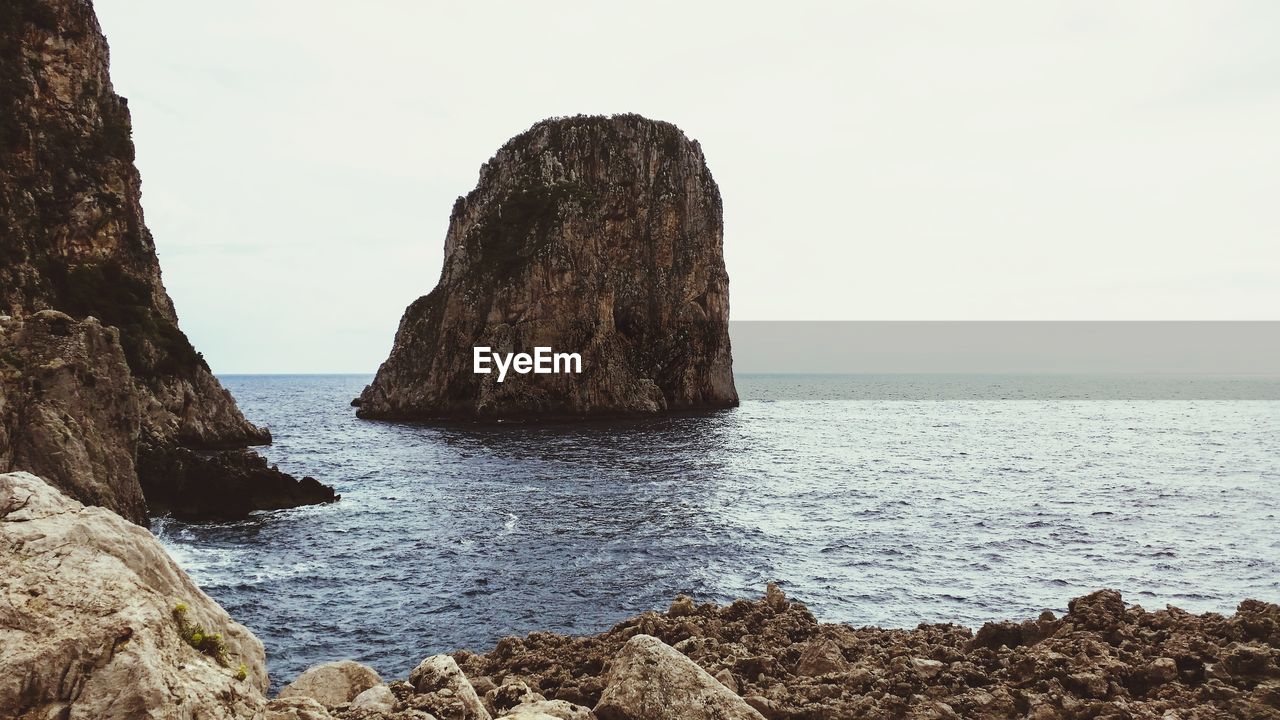 Capri - rocks on sea shore against sky