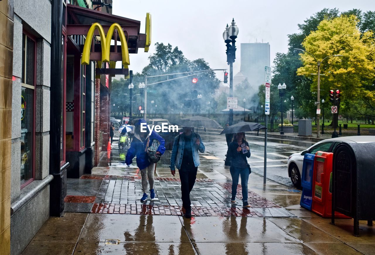 PEOPLE WALKING ON WET STREET IN RAIN