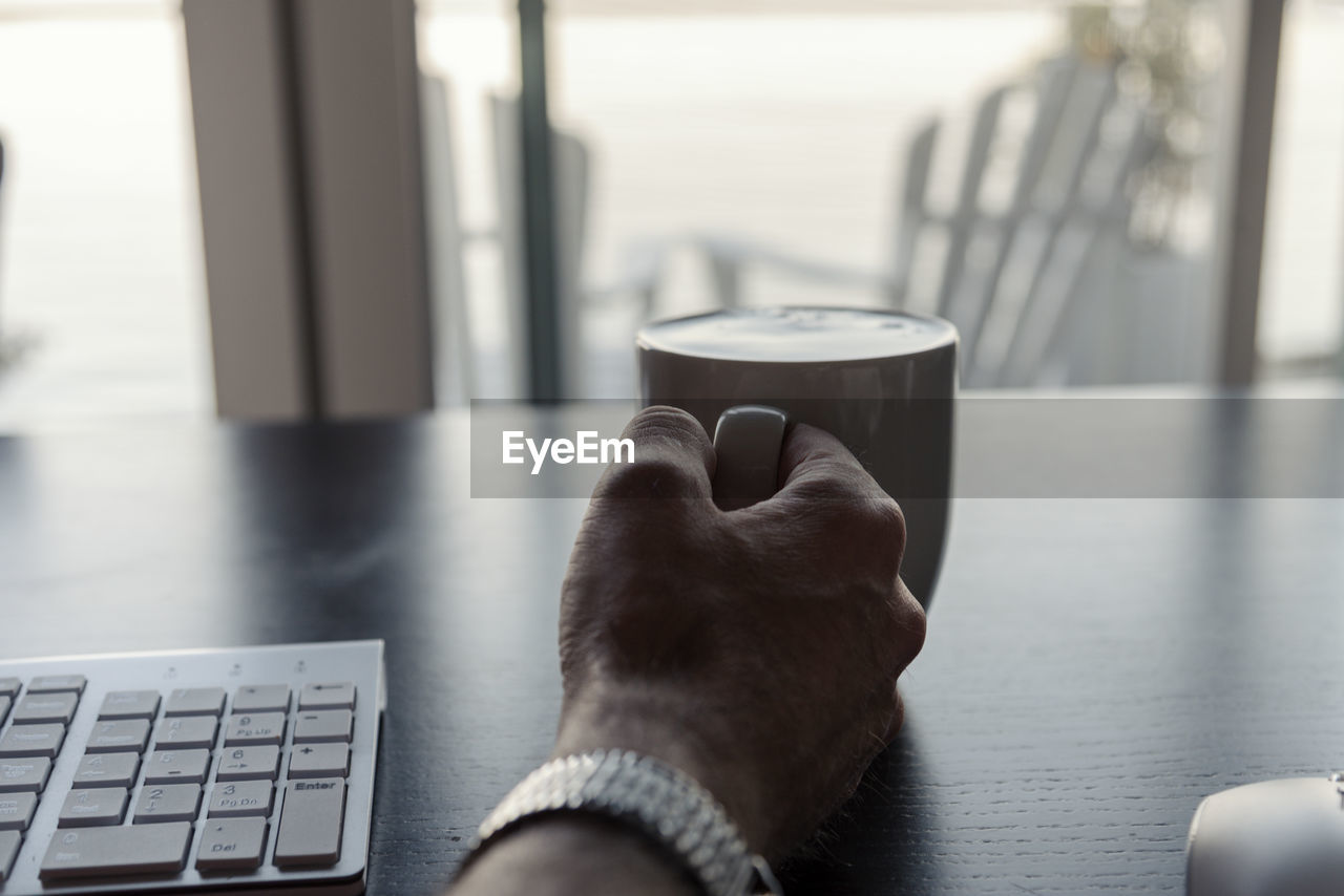 Cropped hand having drink at desk