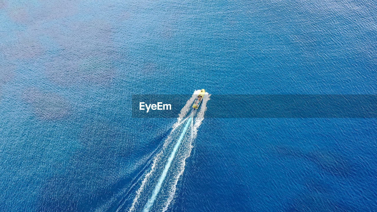 Boat sails in open sea, leaving white wake. drone from bird's eye view. sunny day, light sea waves