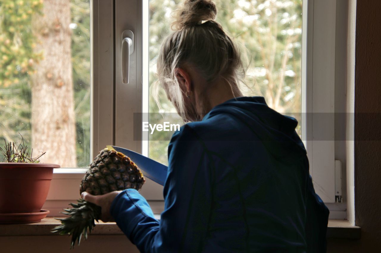Side view of woman holding pineapple at home