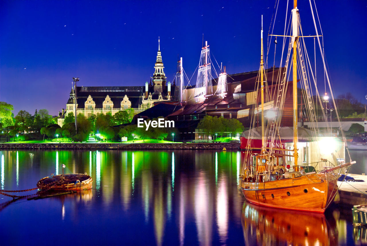 Boats moored at illuminated temple against sky at night