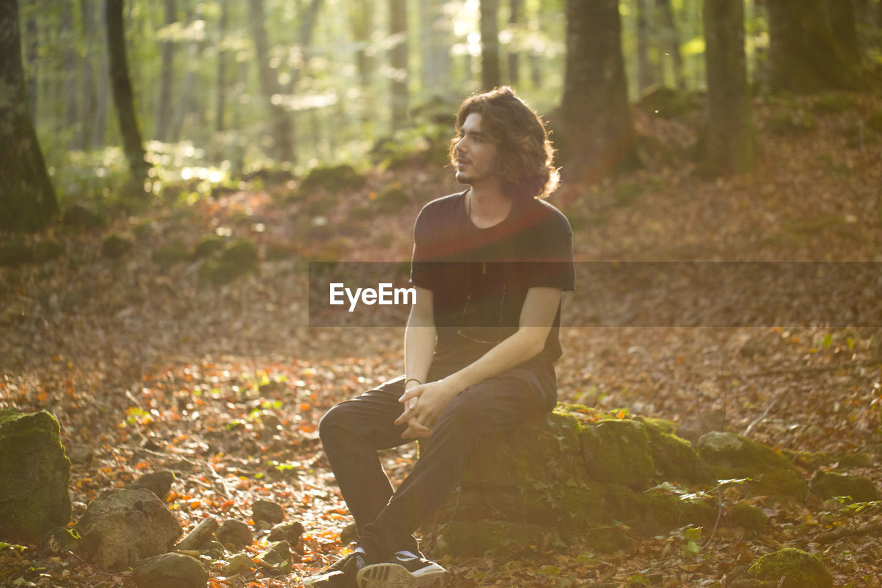 Young man sitting in forest