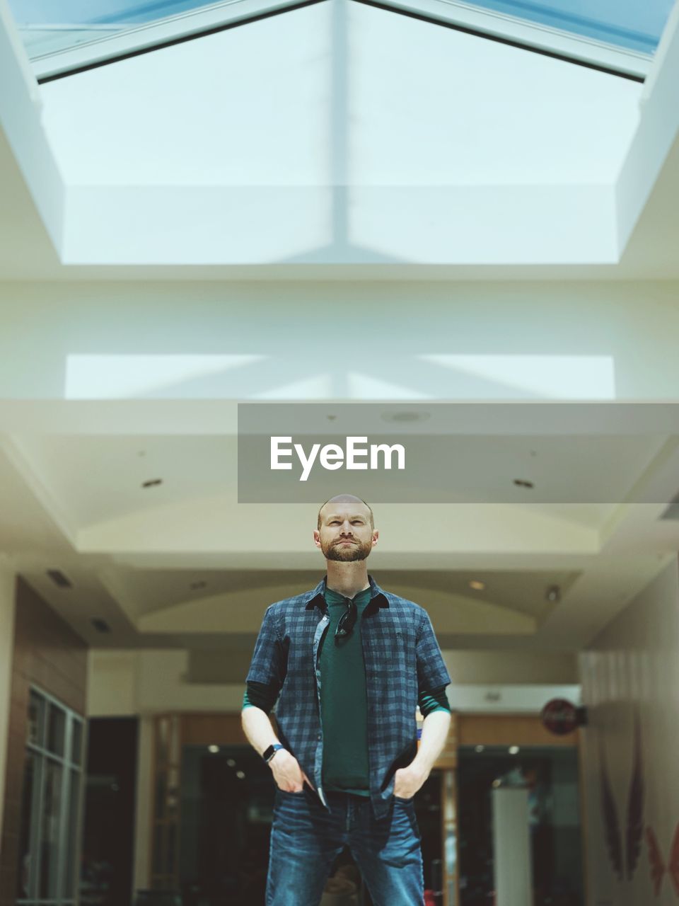 LOW ANGLE VIEW OF YOUNG MAN LOOKING THROUGH CEILING