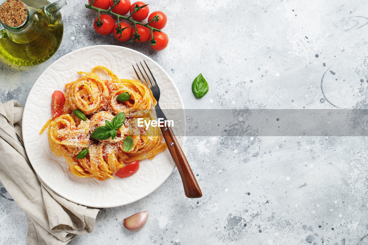 Tasty appetizing classic italian tagliatelle pasta with tomato sauce, cheese parmesan and basil.