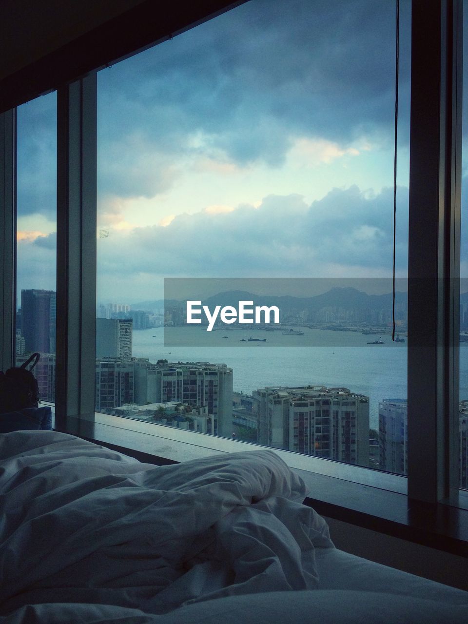 Buildings against cloudy sky seen through glass window