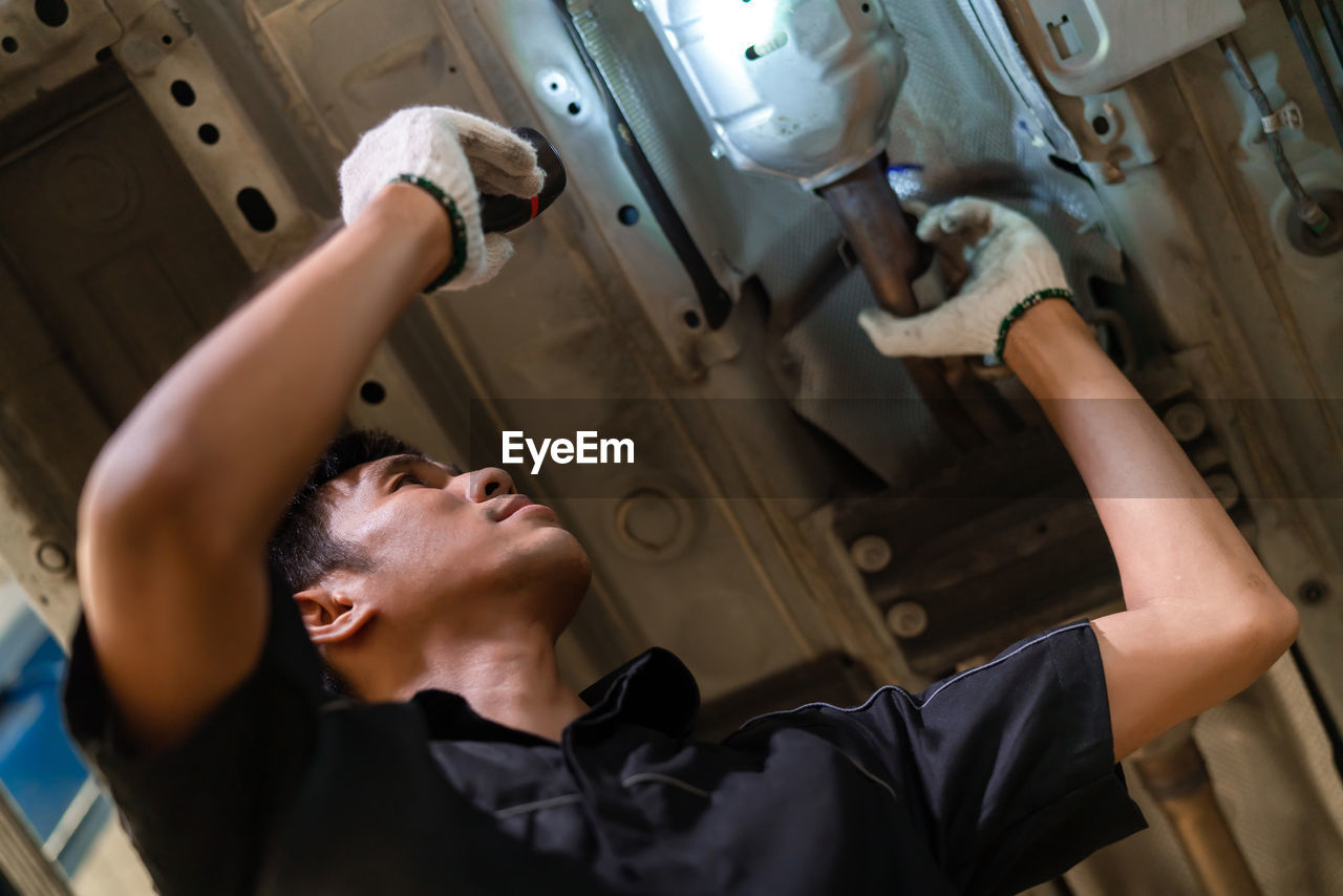 LOW ANGLE VIEW OF YOUNG MAN LOOKING AT CAMERA IN CEILING