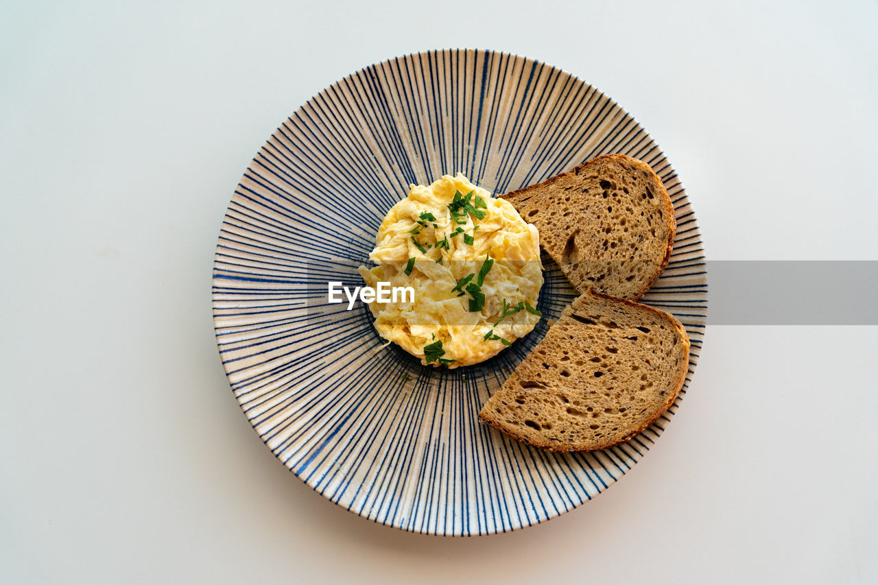 An image of freshly scrambled eggs served with brown bread toast.