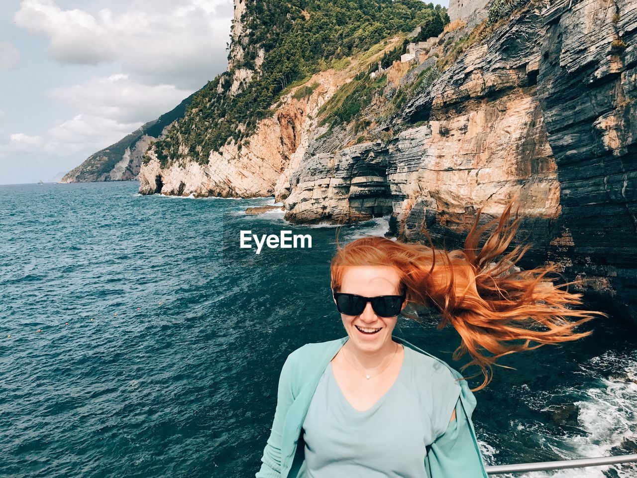 Portrait of cheerful woman against sea