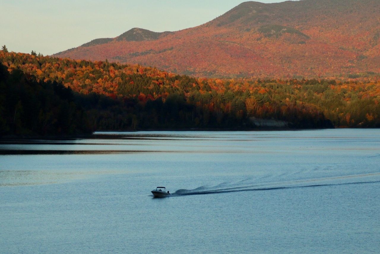 Boat sailing in river against mountains