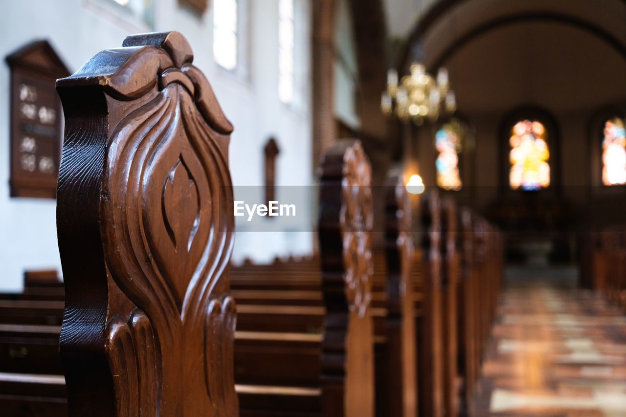 focus on foreground, no people, architecture, indoors, wood, candle, place of worship, religion, building, spirituality, built structure, belief, lighting