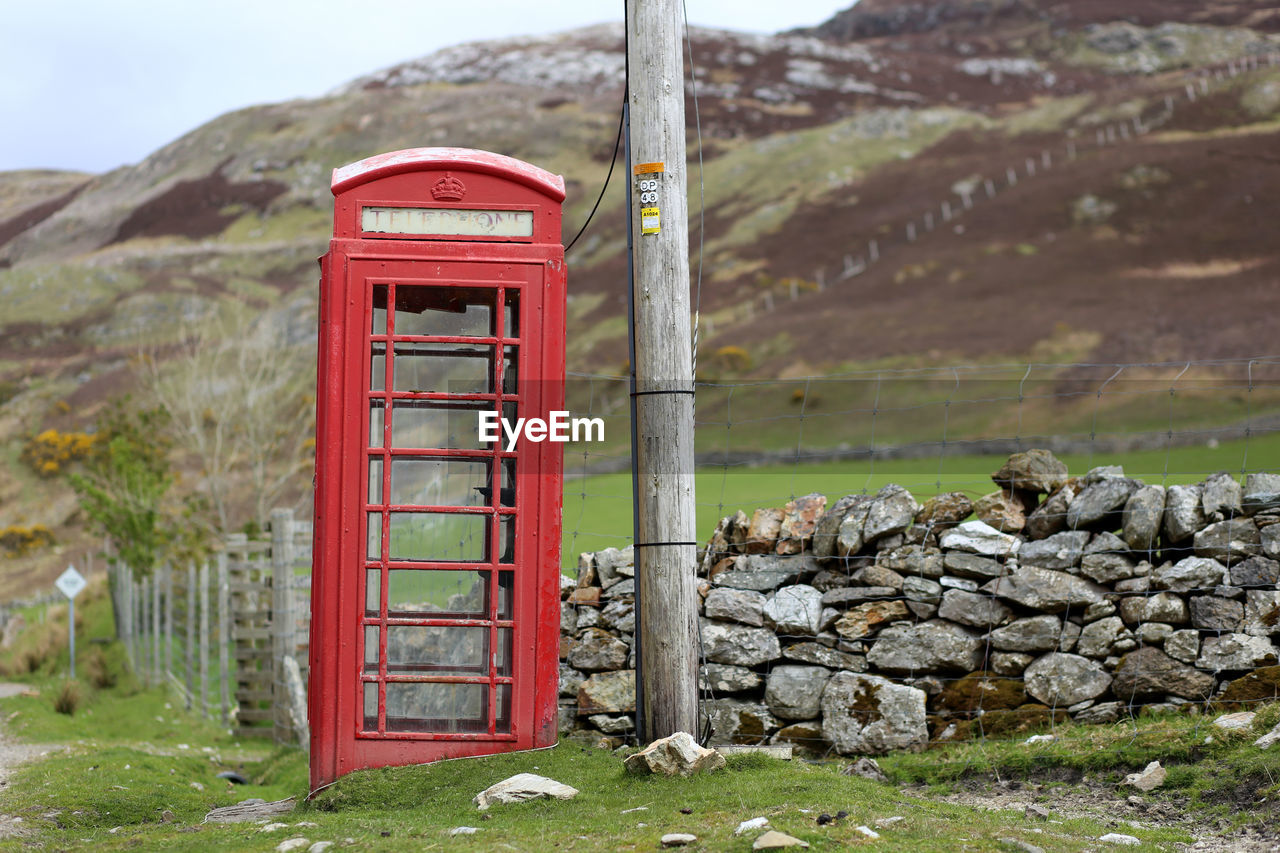 Close-up of telephone booth by mountain against sky