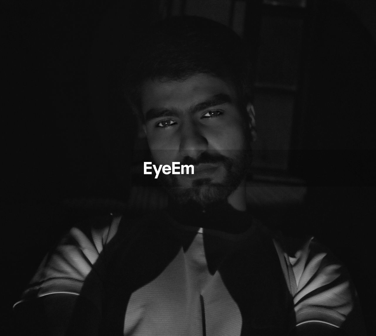 PORTRAIT OF YOUNG MAN IN DARK ROOM
