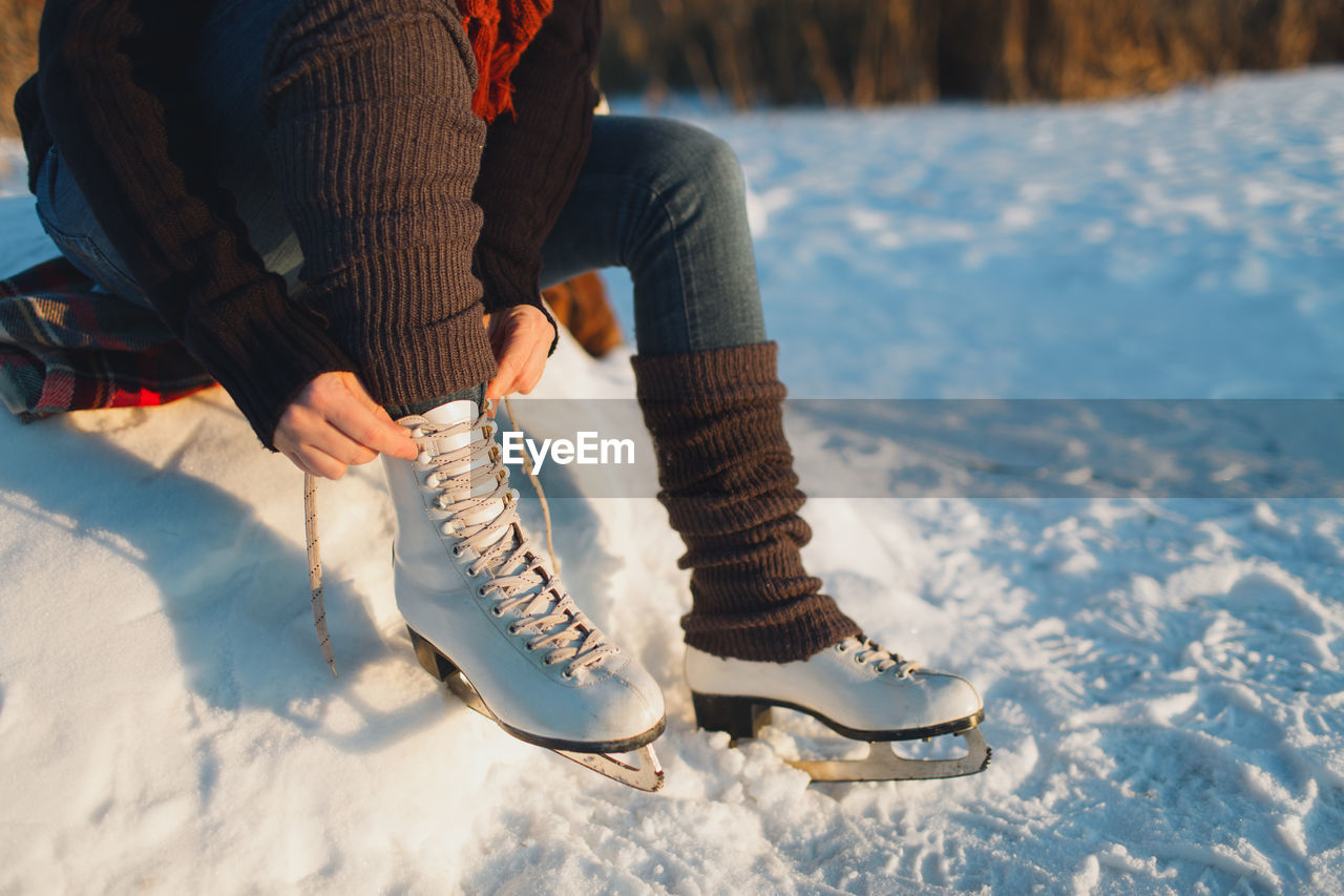 Low section of woman wearing ice skates on frozen lake