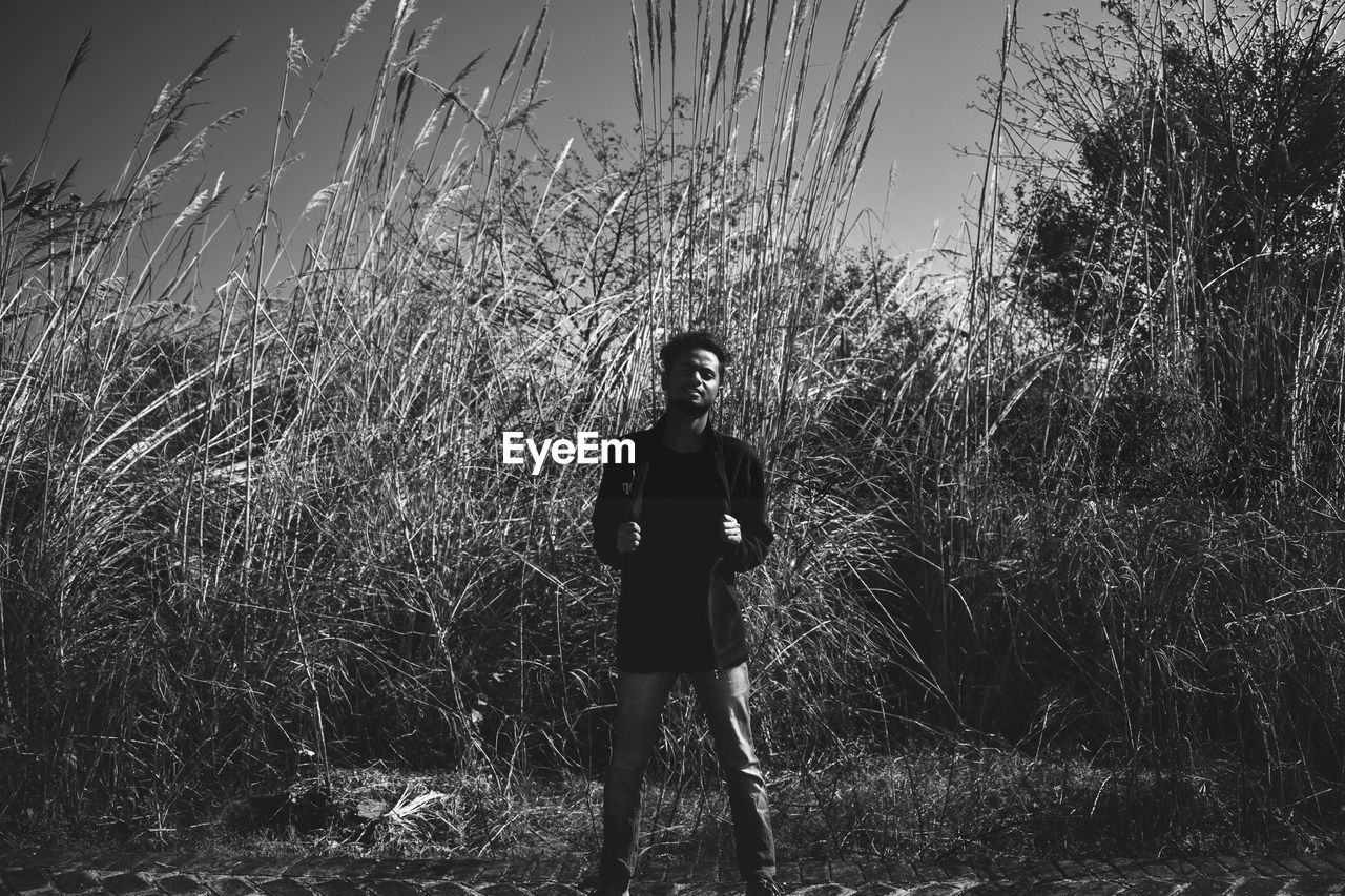 Portrait of young man standing on land against plants