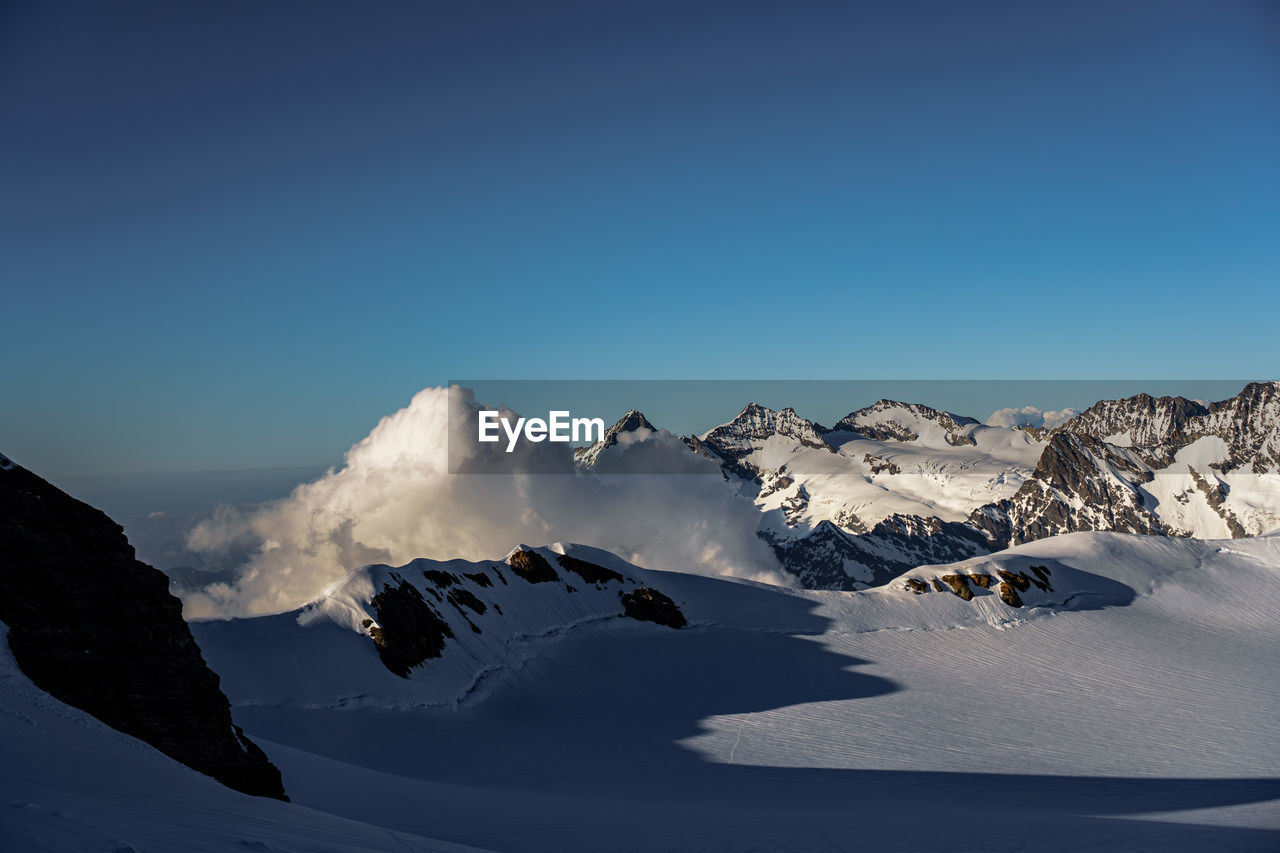 Scenic view of snowcapped mountains against clear blue sky