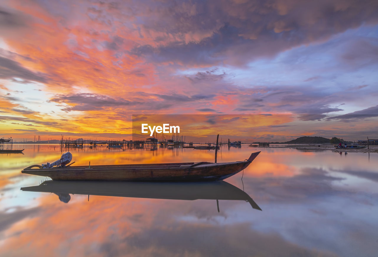 Boats moored on sea against sky during sunset