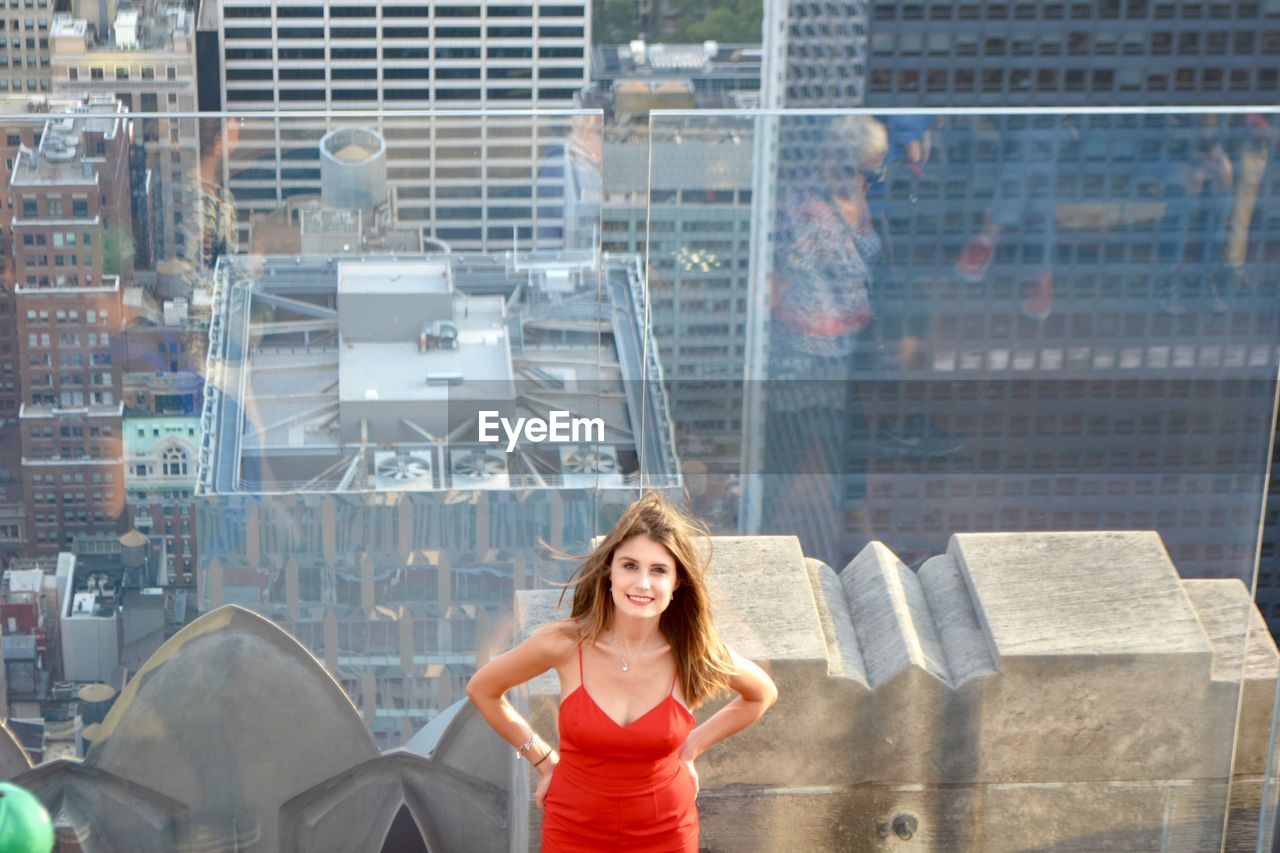 High angle portrait of woman against glass railing in city