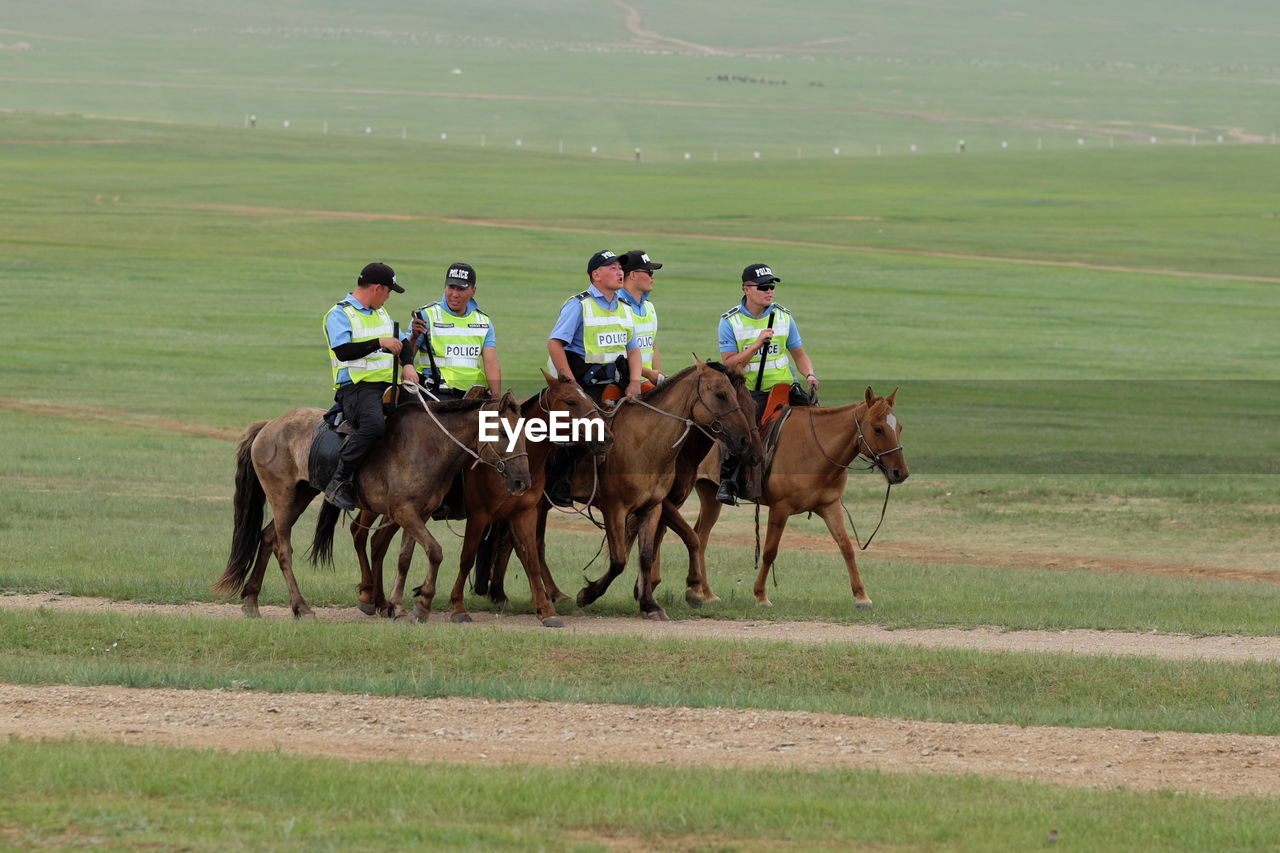 MEN RIDING HORSE ON FIELD