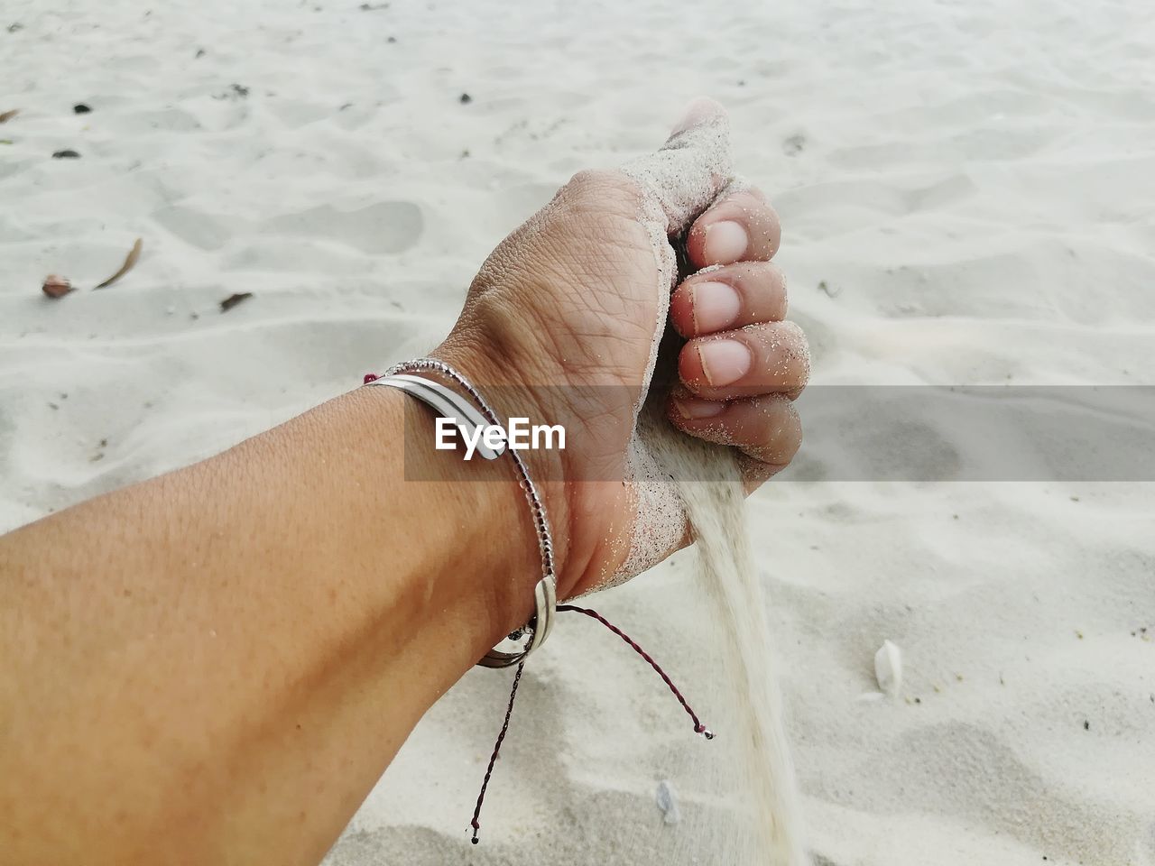 Cropped hand spilling sand at beach