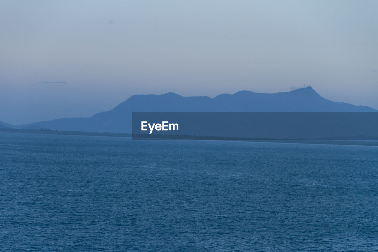 SCENIC VIEW OF SEA AGAINST MOUNTAIN AGAINST CLEAR SKY