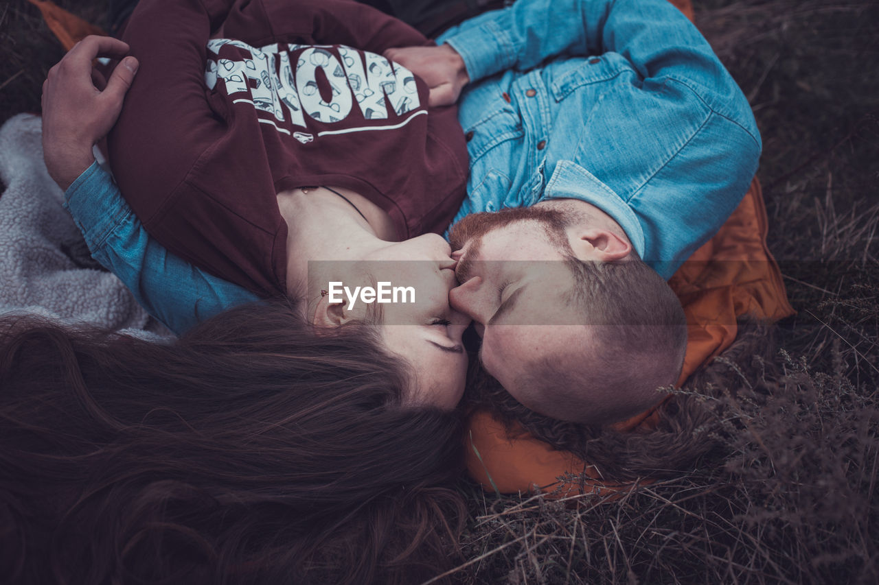 High angle view of couple kissing lying on grass outdoors