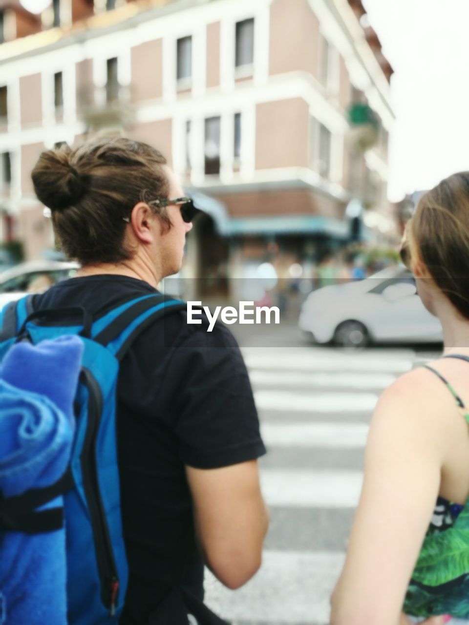 REAR VIEW OF MAN ON STREET AGAINST BUILDINGS