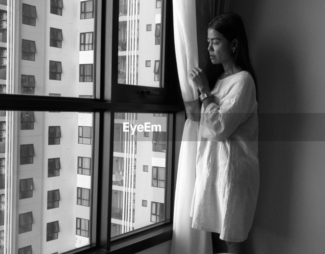 Woman standing by window at home