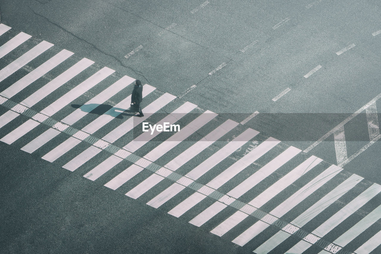 High angle view of man walking on zebra crossing