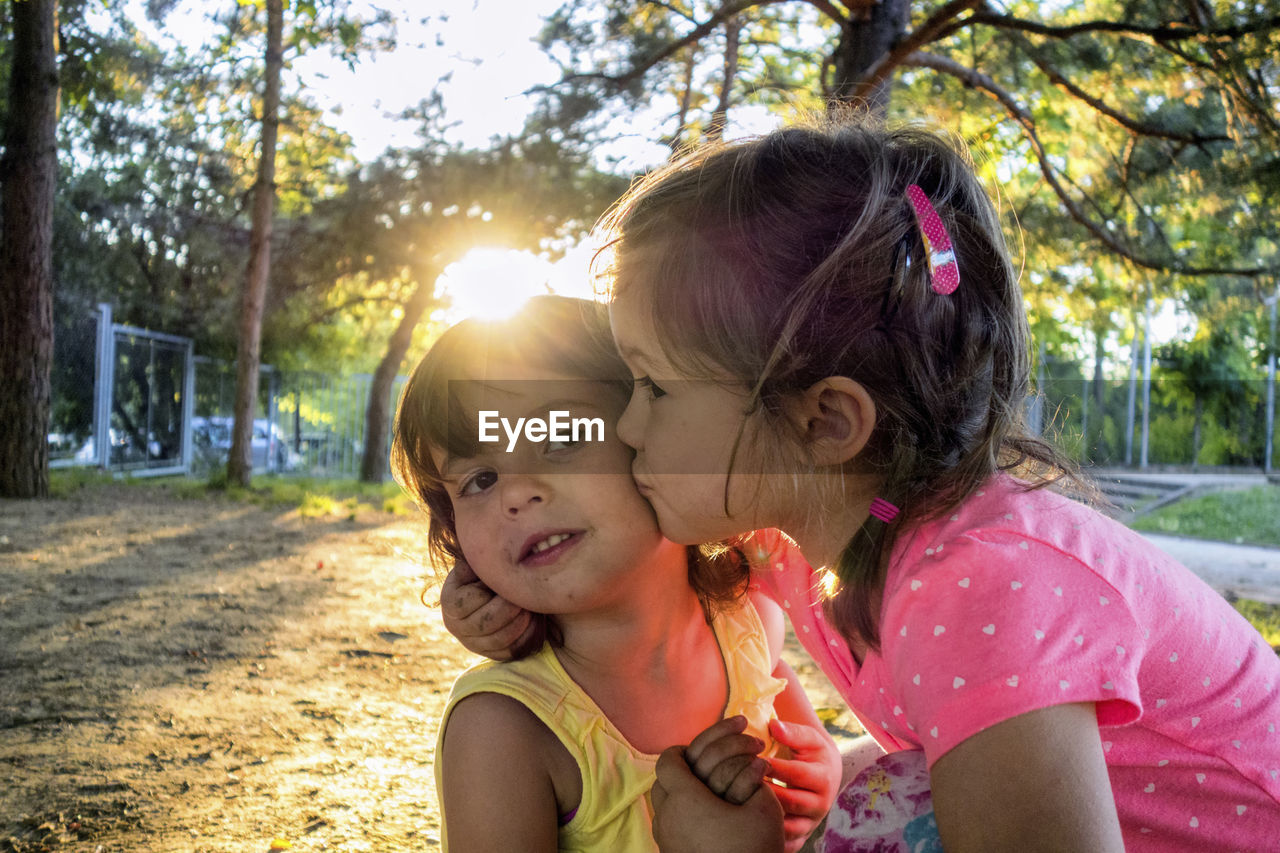 Close-up of cute girl kissing sister at park