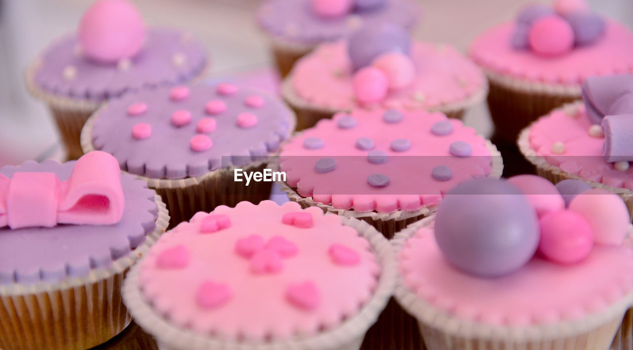 CLOSE-UP OF CUPCAKES ON TABLE AGAINST WALL