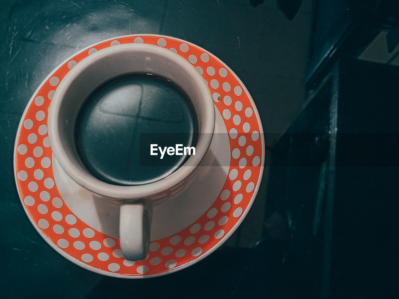 A cup of black coffee with a polka dot glass motif on a black background