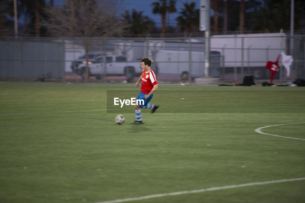 Teen soccer player dribbling the ball during a game