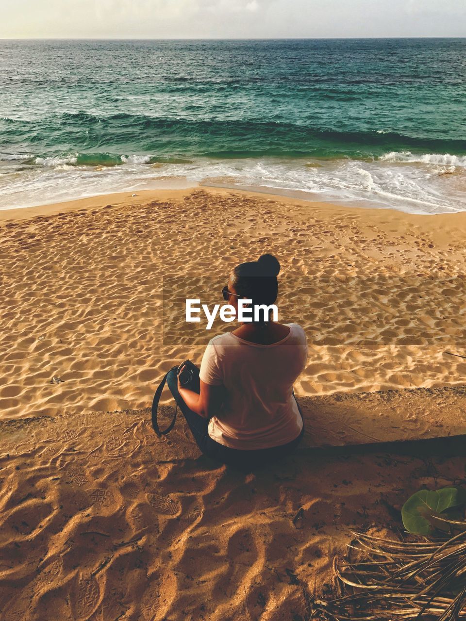 Rear view of woman sitting on sand at beach