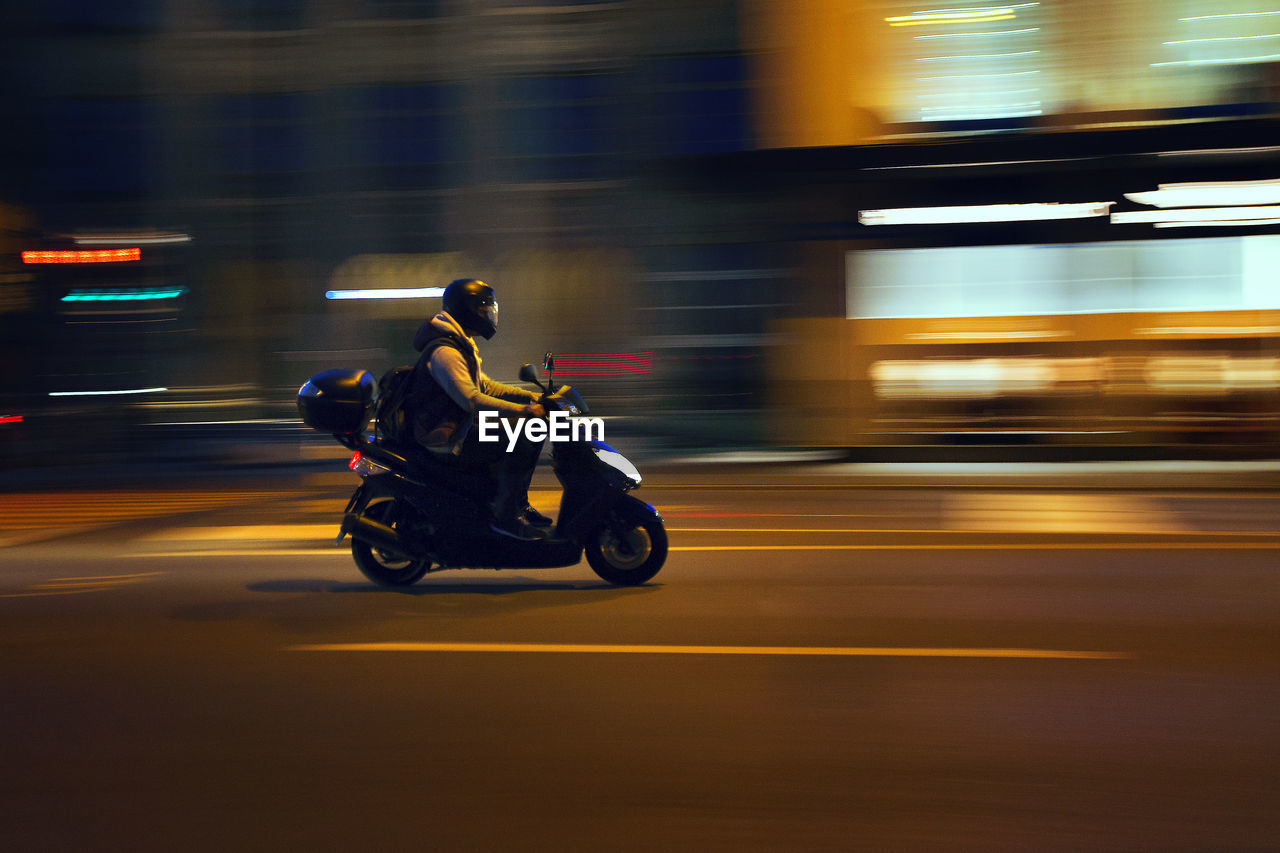 Man riding motorcycle on street at night